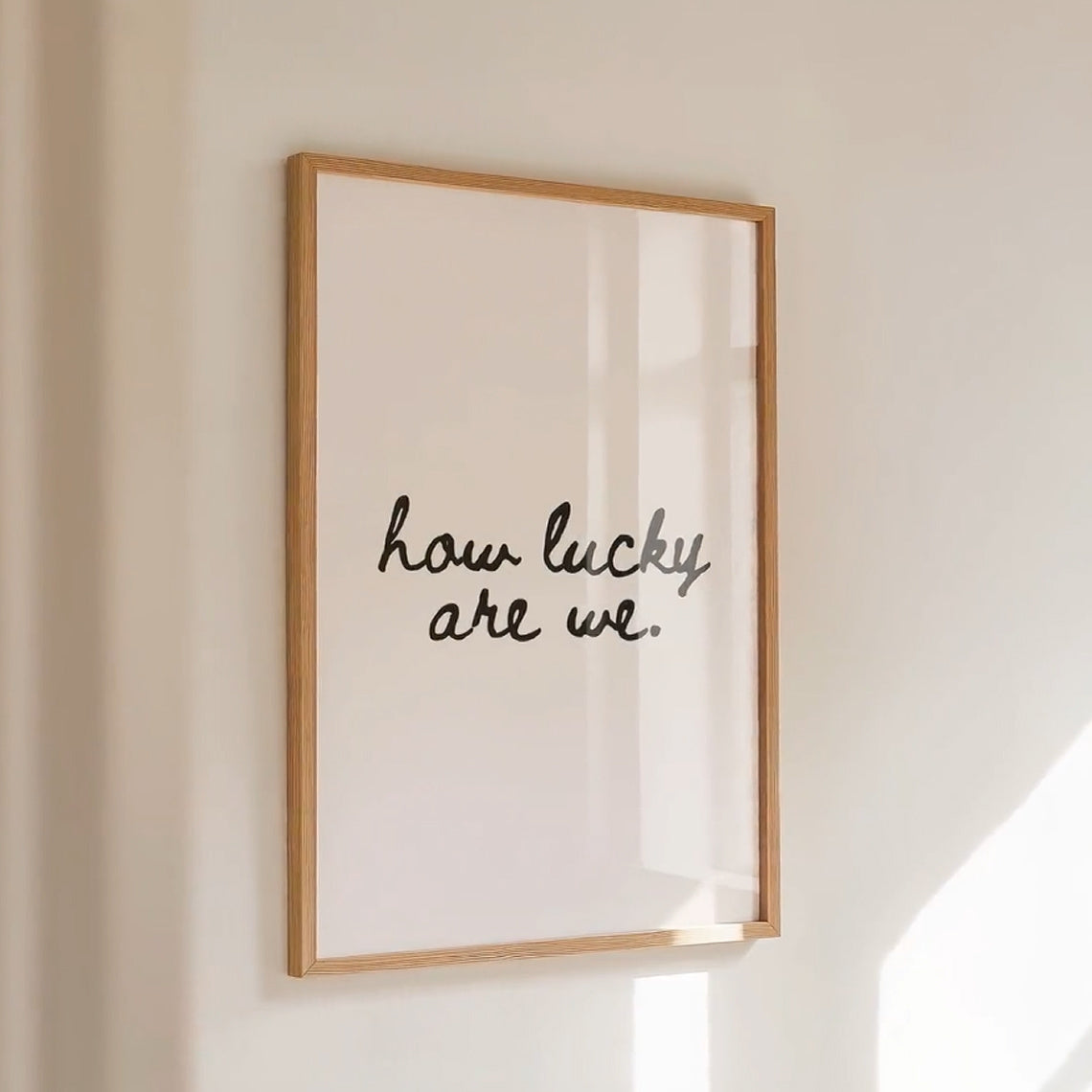 How Lucky We Are Canvas Wall Art, Minimalist Black Script on Cream for Bedroom or Living Room — artwork and room preview